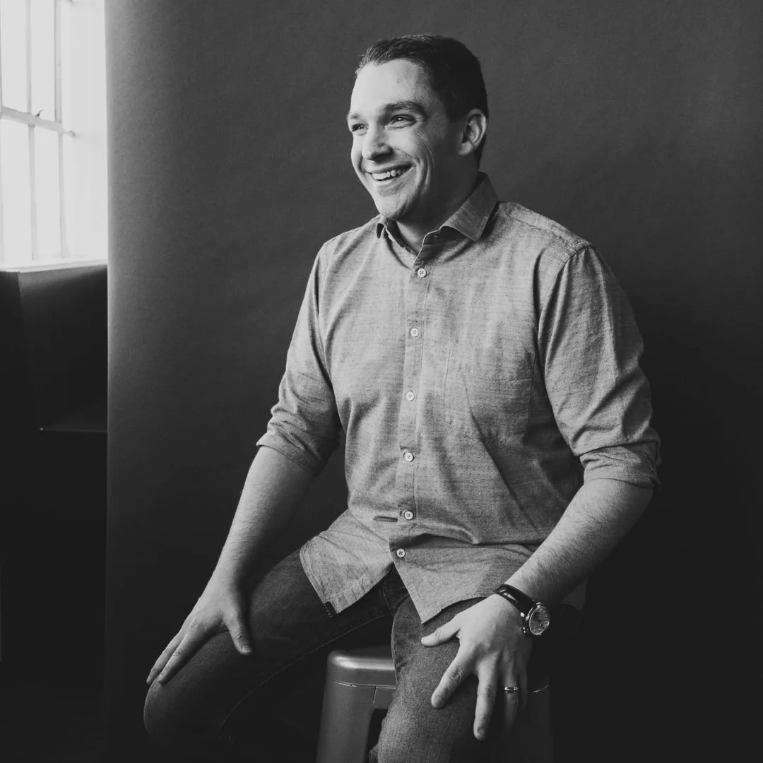 Ryan Deiss seated on a stool, laughing, looking off camera