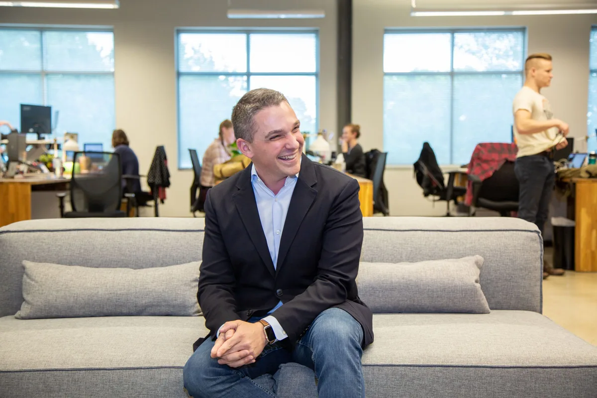 Ryan Deiss seated in an open office with his team working behind him