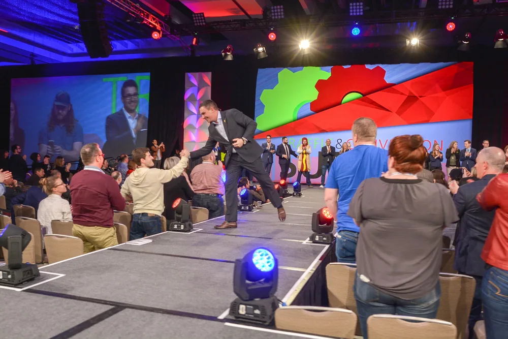 Ryan Deiss coming off stage to shake hands with someone in the audience